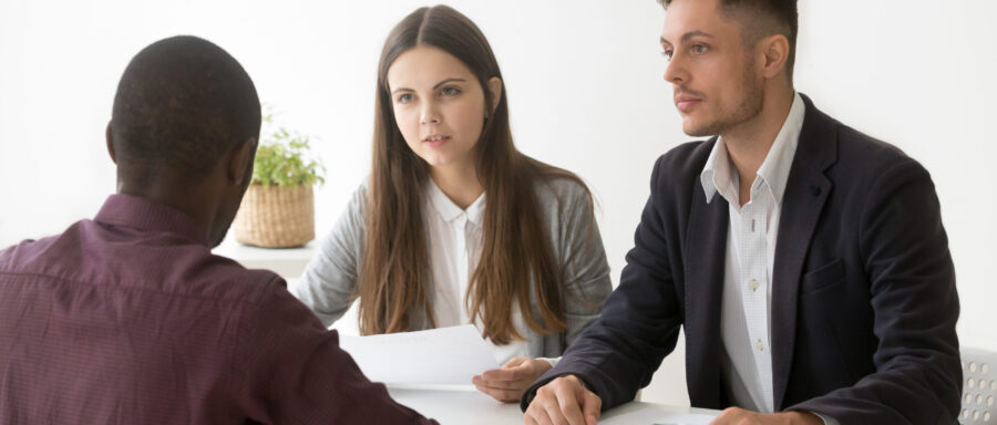 Serious thoughtful caucasian hr managers listen to african applicant at job interview, focused white recruiters ask black candidate questions, recruiting, employment, hiring, first impression concept